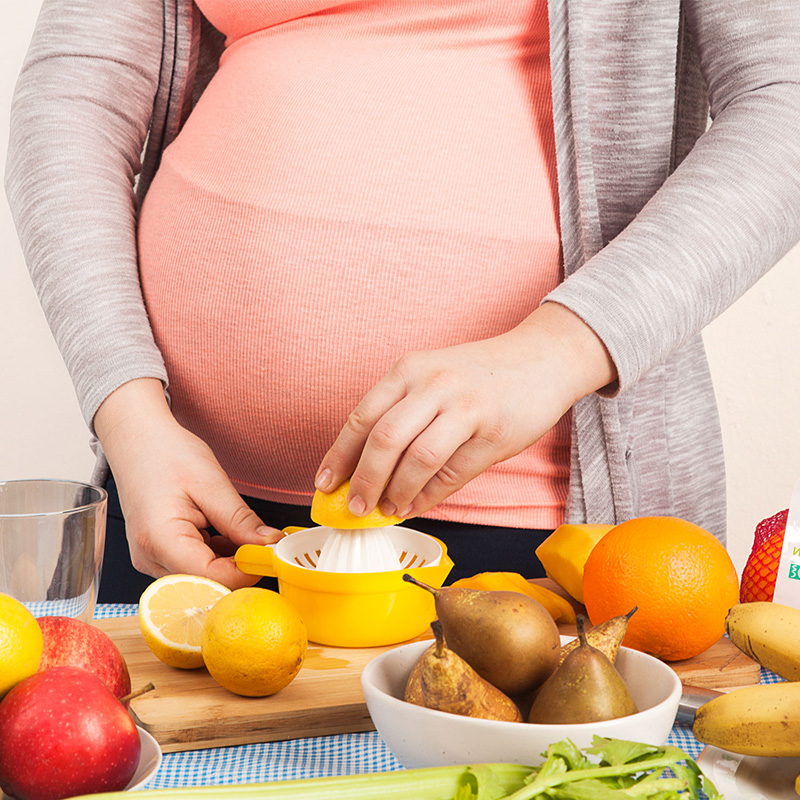trudnica cedi limun, vidi se stomak i ruka u krupnom planu